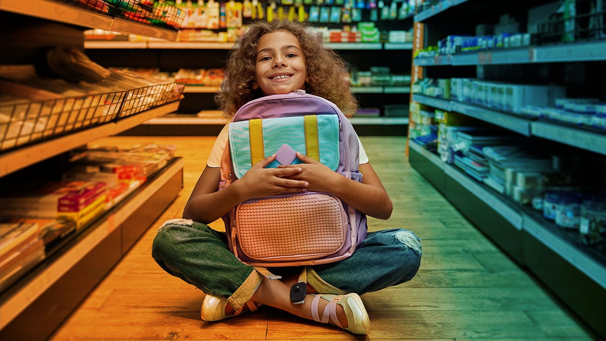 Happy girl sitting on floor hugging new backpack for back-to-school