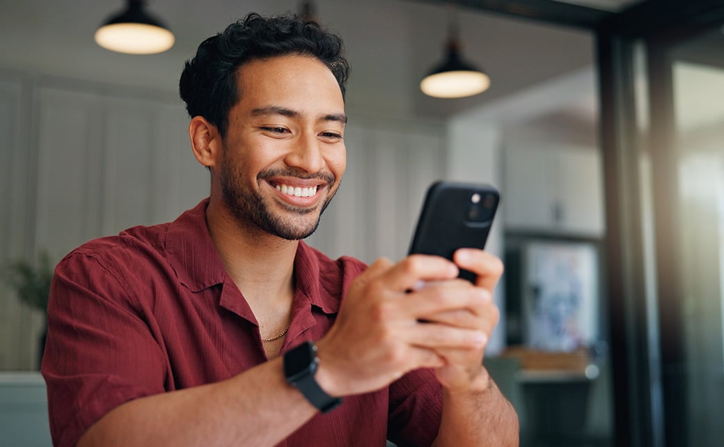 Smiling man typing on smartphone