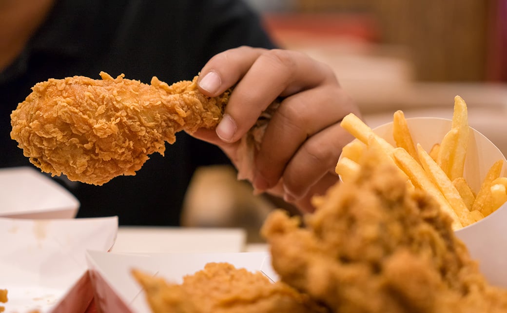 person eating fried chicken drumstick